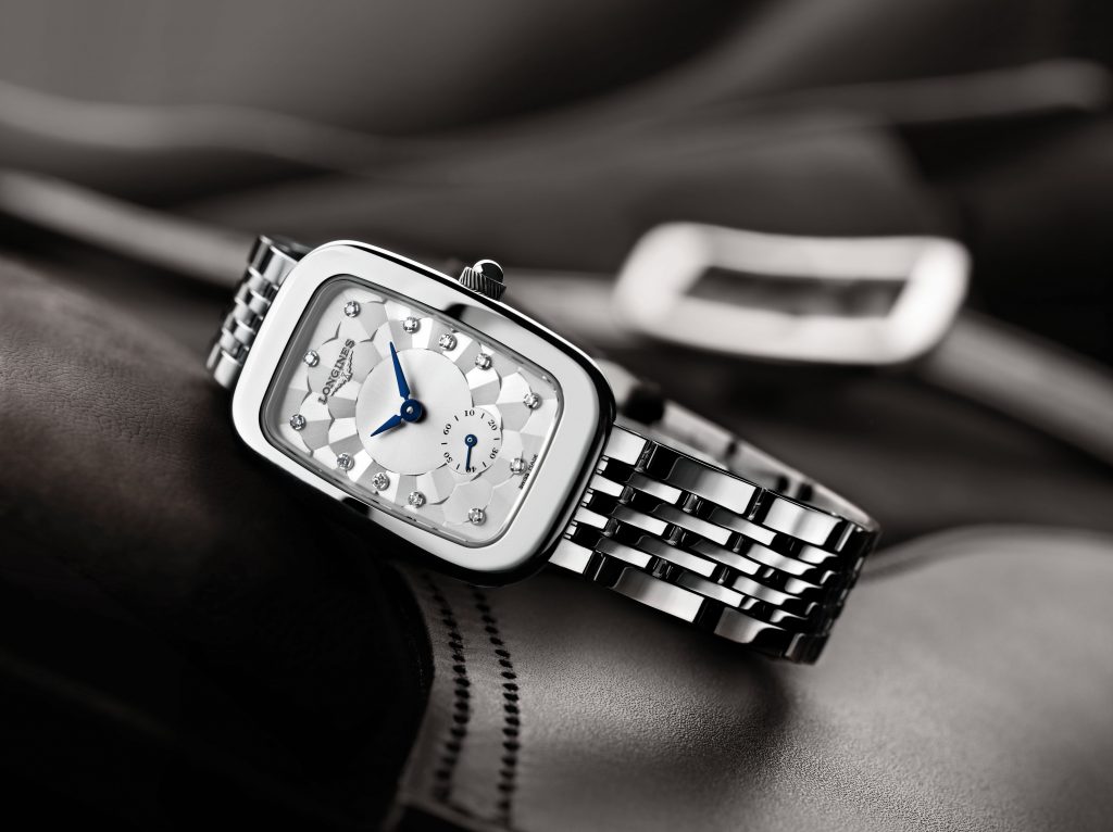 in the shape of its stainless-steel case, this Longines Equestrian timepiece features a silver-coloured “damier” dial enhanced by blued-steel hands and adorned with diamond indexes. The polished stainless-steel case and bracelet are further enhanced by the 60 Wesselton VVS diamonds, for a total of 0.504 carats, surrounding its bezel.